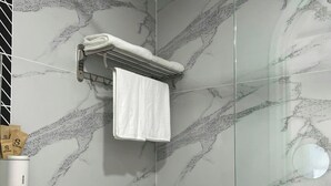 Une salle de bain moderne avec un pare-baignoire en marbre, une douche en verre, des toilettes et un porte-serviettes avec une serviette.