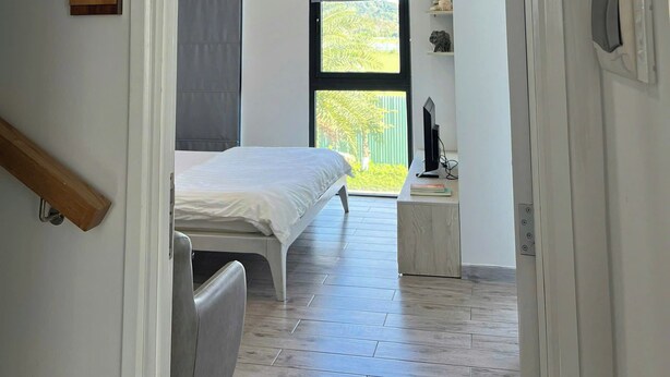 Une chambre à coucher avec un lit, un bureau, une chaise, une fenêtre et une porte.