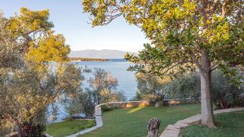 A landscaped area with a pathway, trees, and a view of a body of water.