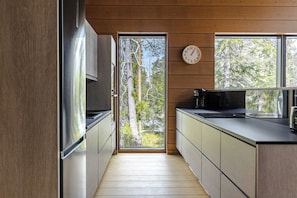 Une cuisine moderne avec des murs en bois, une grande fenêtre et une horloge au mur.
