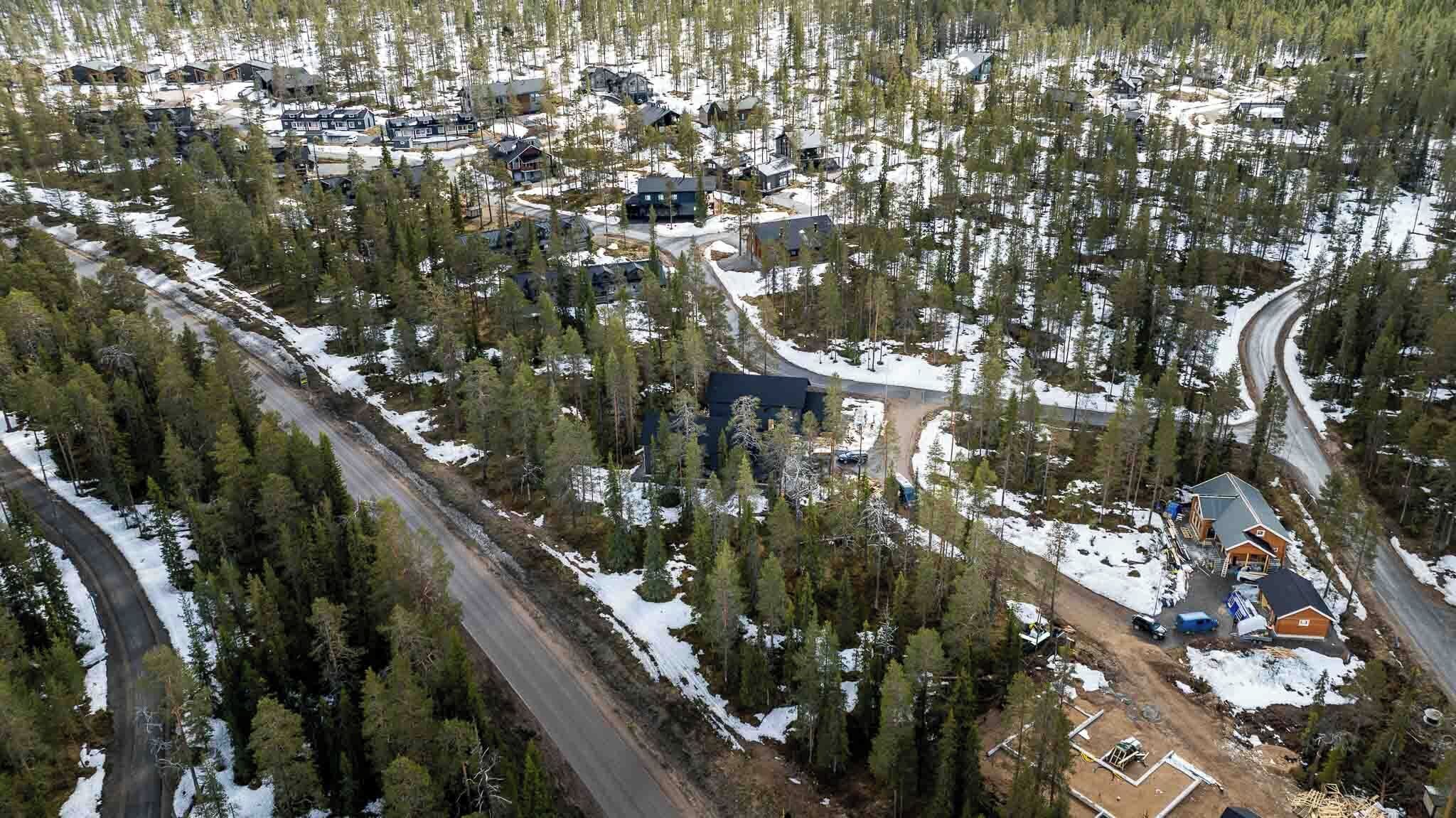 An aerial view of a residential area with houses, roads, and a forested landscape.