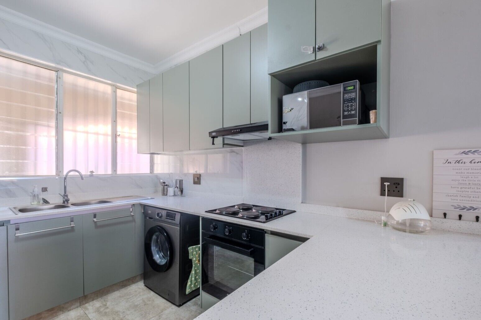 A modern kitchen with a built-in washing machine, a microwave, and a gas stove.