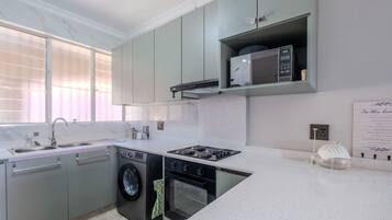 A modern kitchen with a built-in washing machine, a microwave, and a gas stove.