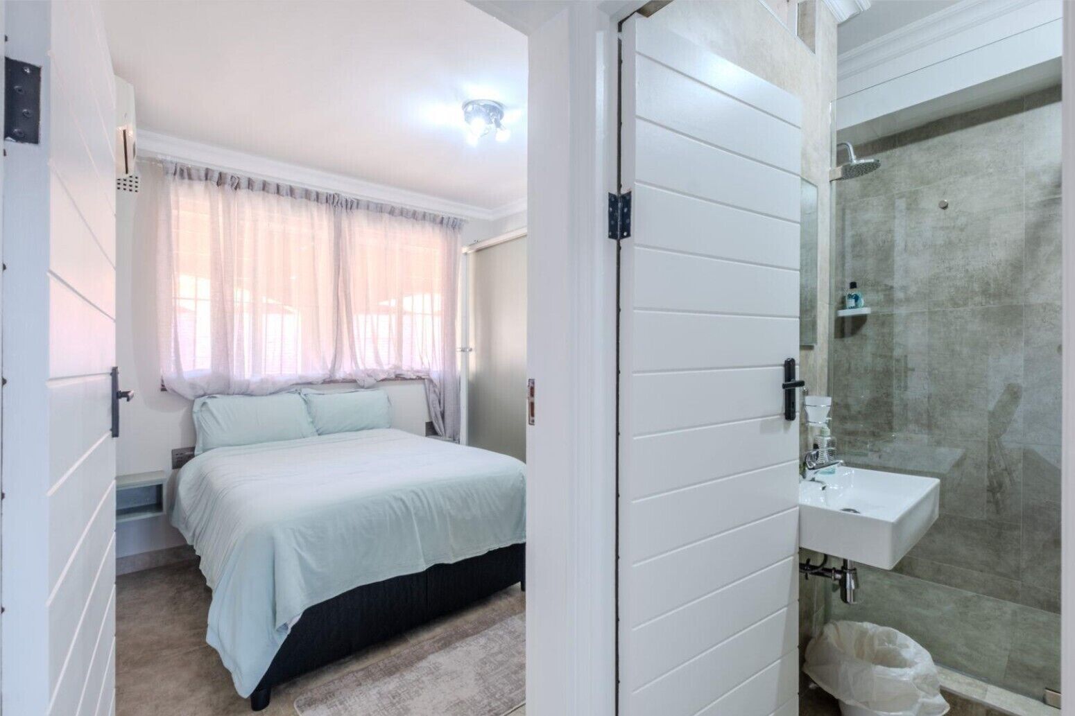 A bedroom with a bed, a bathroom with a shower, and a toilet.