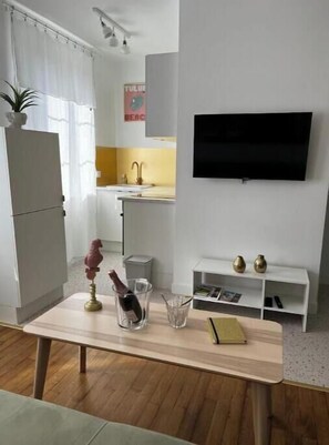 A modern kitchen with a TV, a dining table with a vase, and a small white shelf. - La Verrière ISAHORA - Bright apartment in the heart of the royal city of Eu (Eu)