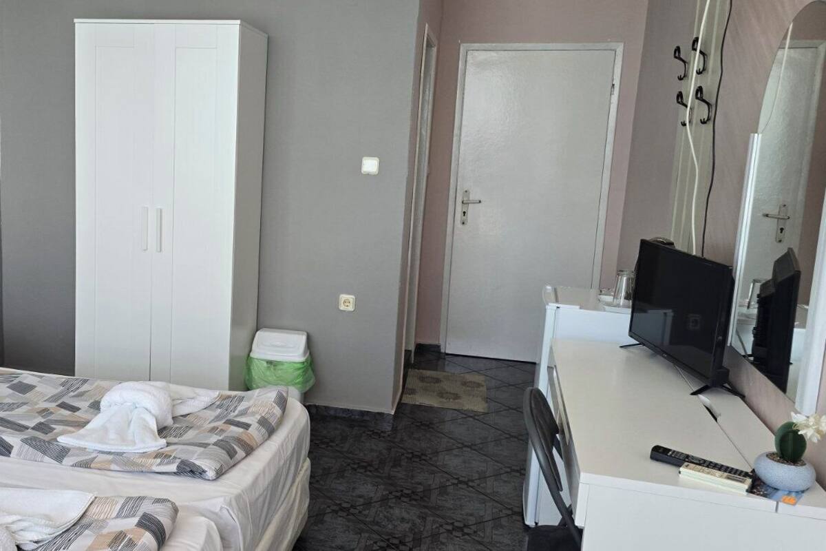 A bedroom with a bed, a wardrobe, a television, and a bathroom door.