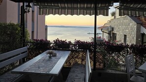 Une terrasse avec une table et des chaises, donnant sur un plan d’eau et des bâtiments.
