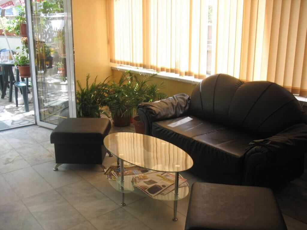 Una sala de estar con una mesa de centro de vidrio, un sofá y una mesita con revistas.