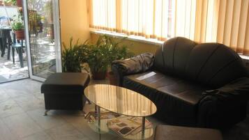 Una sala de estar con una mesa de centro de vidrio, un sofá y una mesita con revistas.