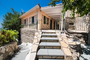 A stone house with a stone staircase leading to a porch. - Almondtree House Exanthia - Private Parking (Lefkada)