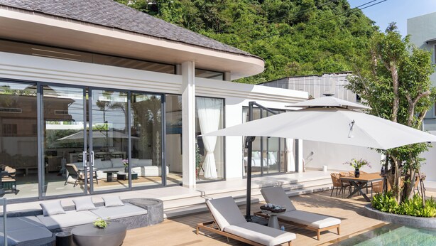 A modern outdoor pool area with lounge chairs, a dining table, and a large umbrella. - Étoile Kata Luxury Pool Villas by Astra (Karon)