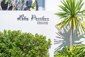 A sign for Lotus Pavilion with a white background and green foliage in the foreground. - Étoile Kata Luxury Pool Villas by Astra (Karon)