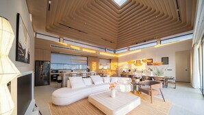A modern living room with a sectional sofa, a coffee table, and a dining area with a table and chairs. - Étoile Kata Luxury Pool Villas by Astra (Karon)