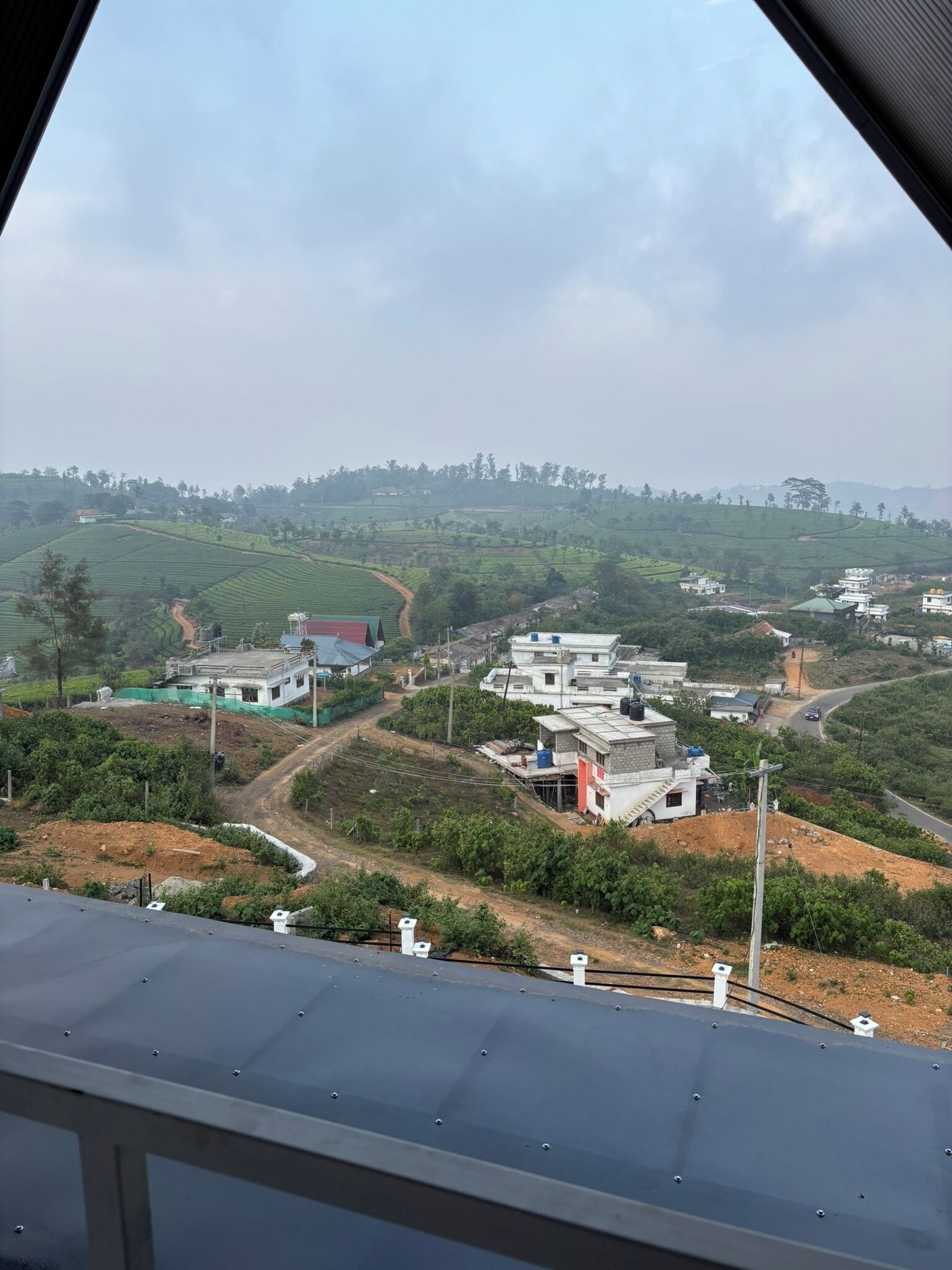 A rural landscape with terraced fields, a winding road, and several buildings with flat roofs.