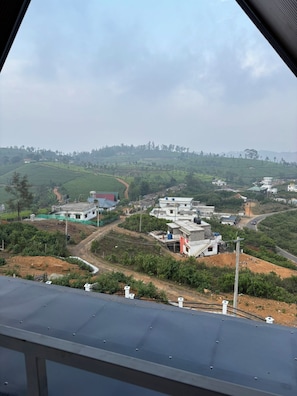 A rural landscape with terraced fields, a winding road, and several buildings with flat roofs.