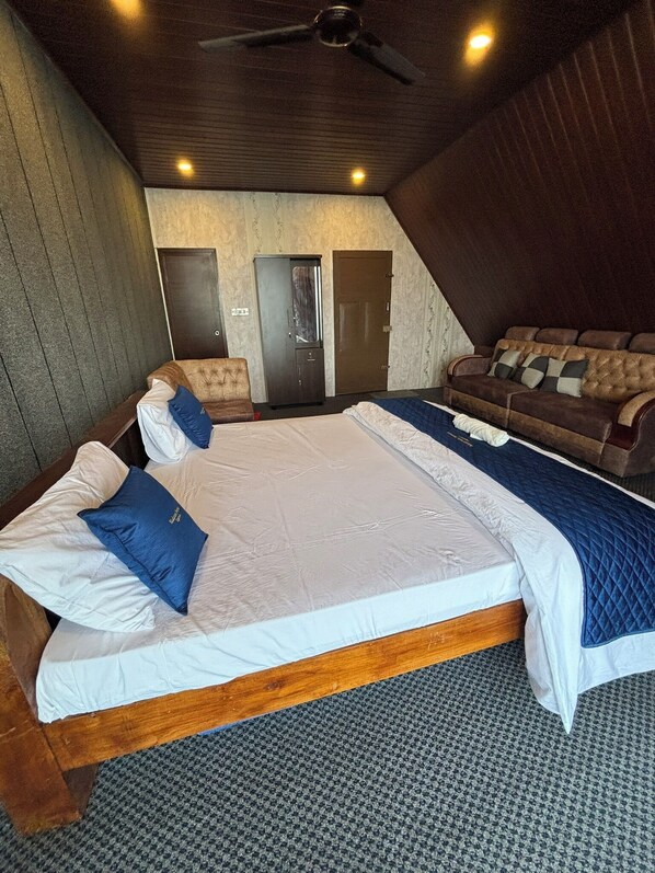 Une chambre à coucher avec un grand lit, un canapé, un ventilateur de plafond et deux portes.