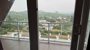 Una habitación con un amplio ventanal que ofrece vistas a un paisaje montañoso con edificios y vegetación.