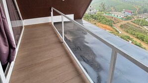Un balcón con vista a un paisaje verde y un edificio a lo lejos.