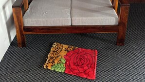 Un sofá de madera con cojines grises en una habitación con alfombra estampada.