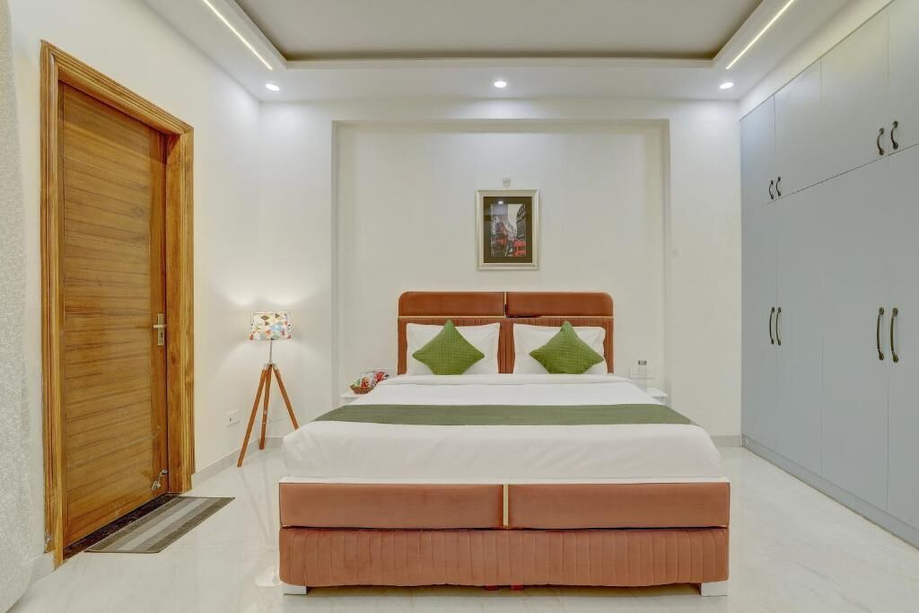 A bedroom with a bed, a wardrobe, a door, and a framed picture on the wall.