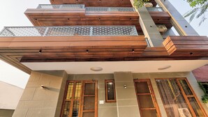 A multi-story building with wooden balconies, large windows, and a modern architectural design. - Alaya Stays Freesia 3BHK Apartment (Greater Noida)
