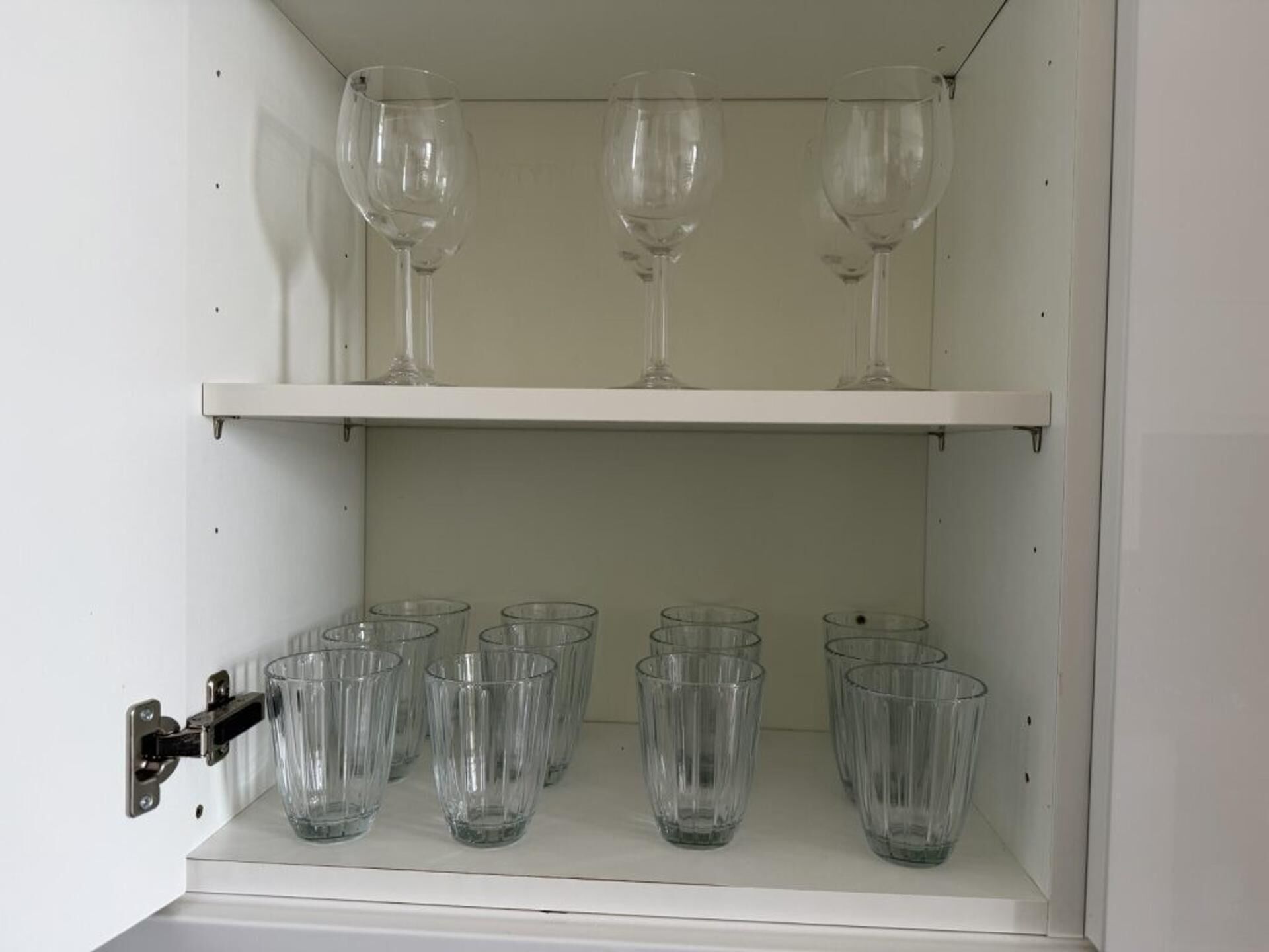 Ein Schrank mit zwei Einlegeböcken; der obere Boden enthält drei Weingläser, und der untere Boden sechs klare Gläser.