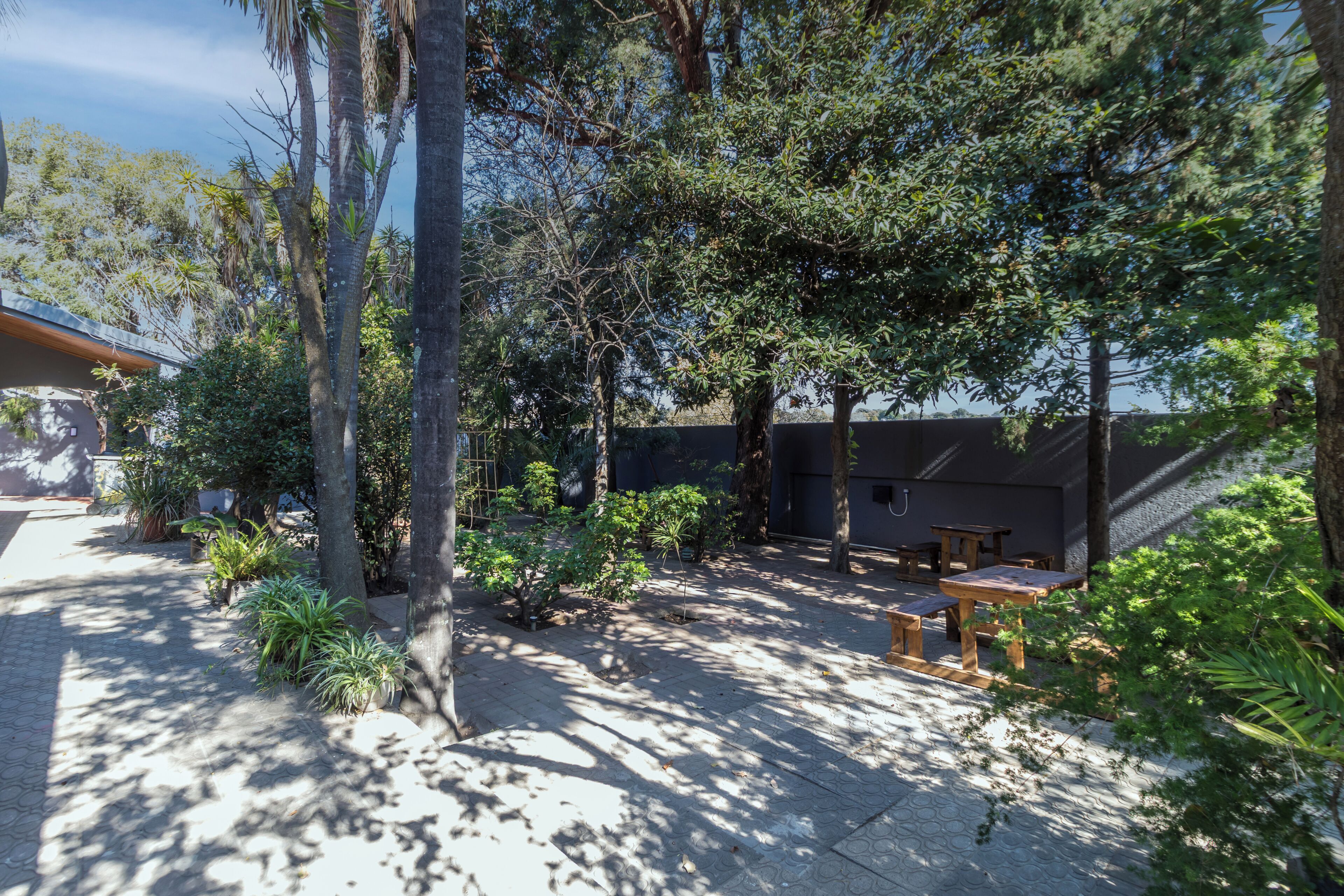 A courtyard with trees, a covered seating area, and a building with a sloped roof.