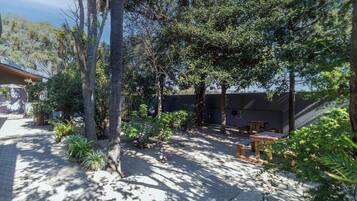 A courtyard with trees, a covered seating area, and a building with a sloped roof.