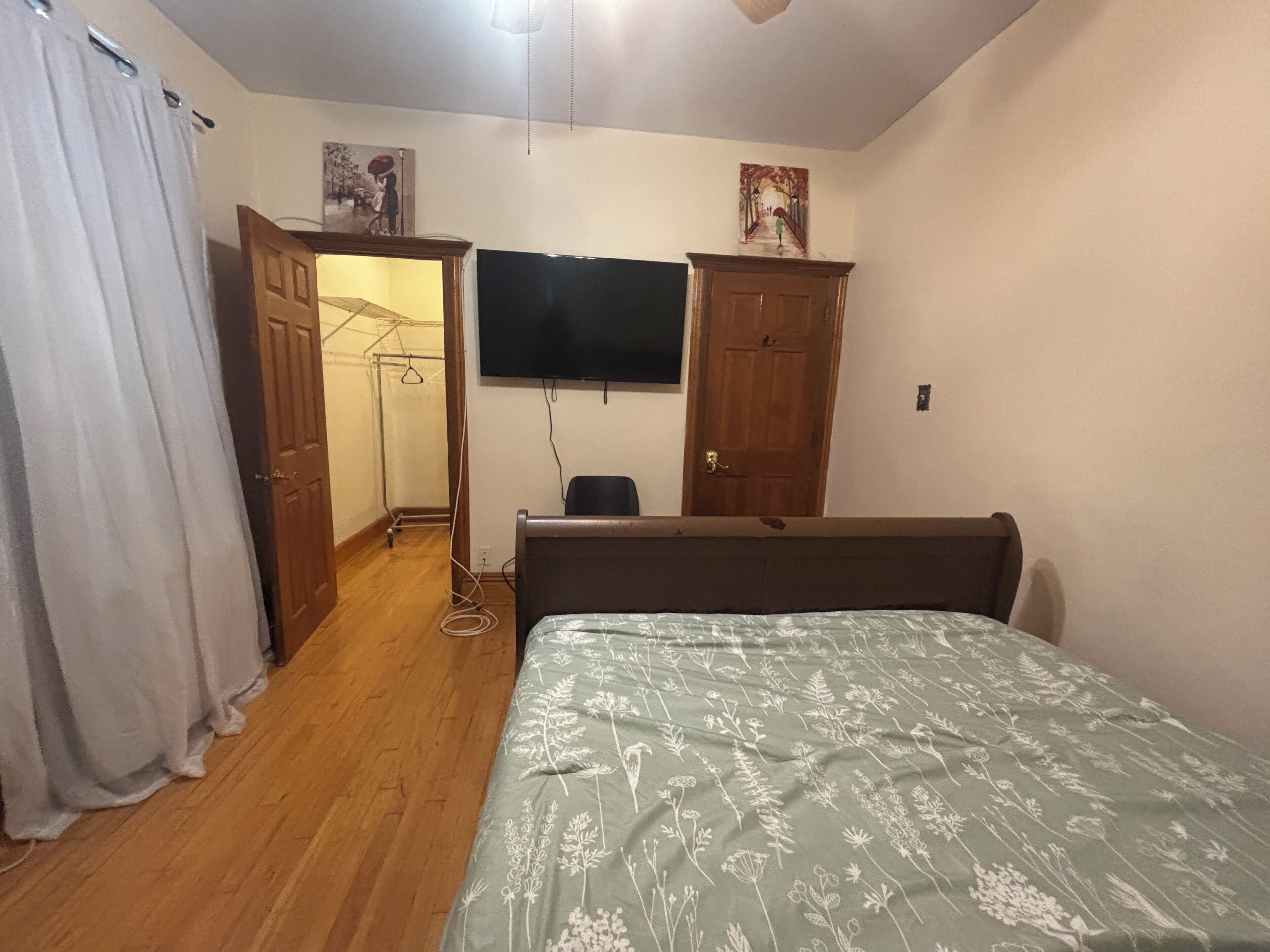A bedroom with a bed, a wardrobe, a television, and a door leading to another room.