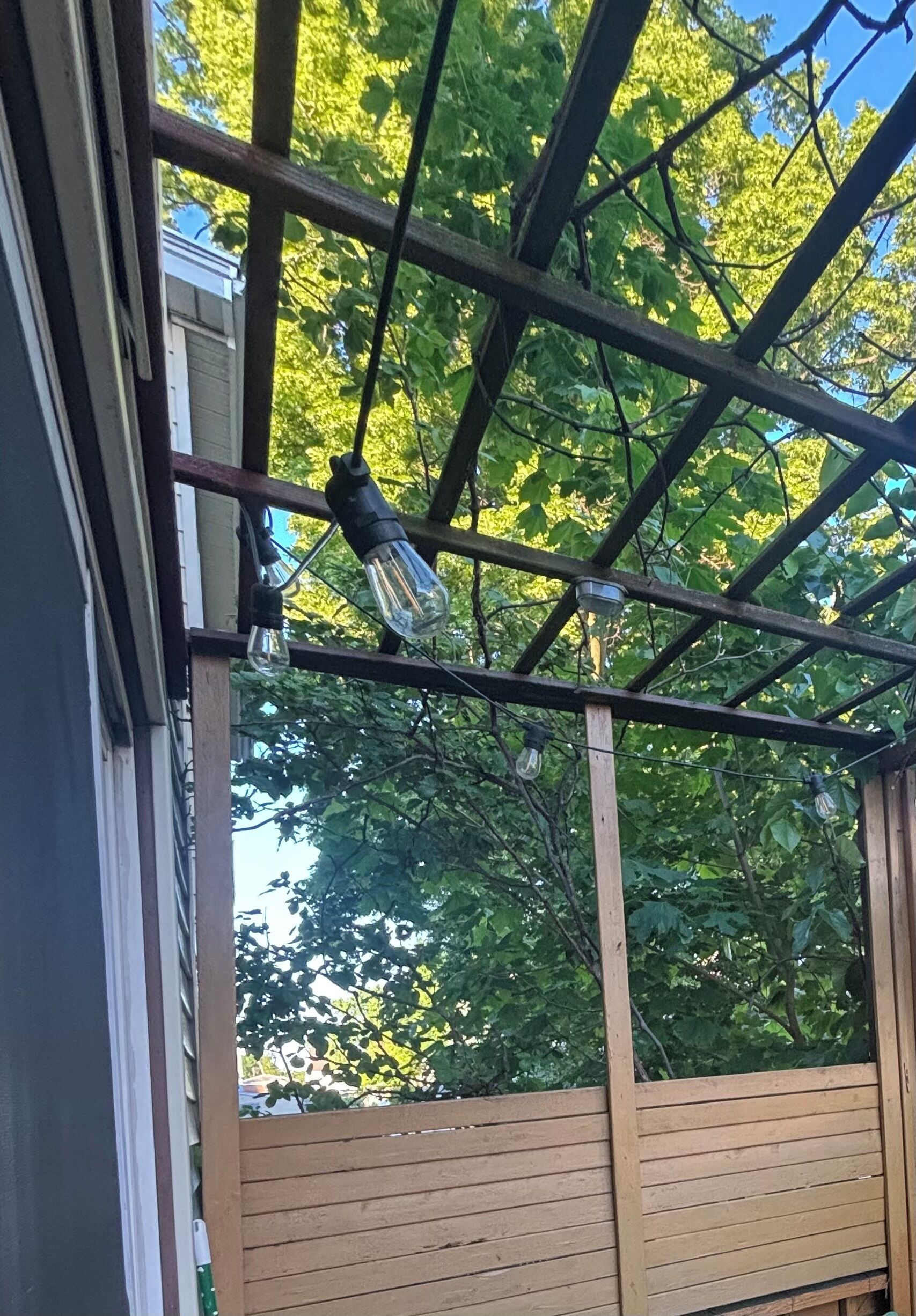 A wooden pergola with a metal frame and hanging light fixtures.