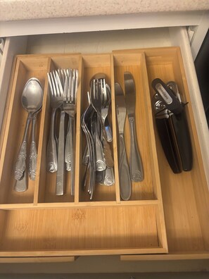 Eine Schublade mit ordentlich sortiertem Besteck, darunter Löffel, Gabeln, Messer und eine Zange.