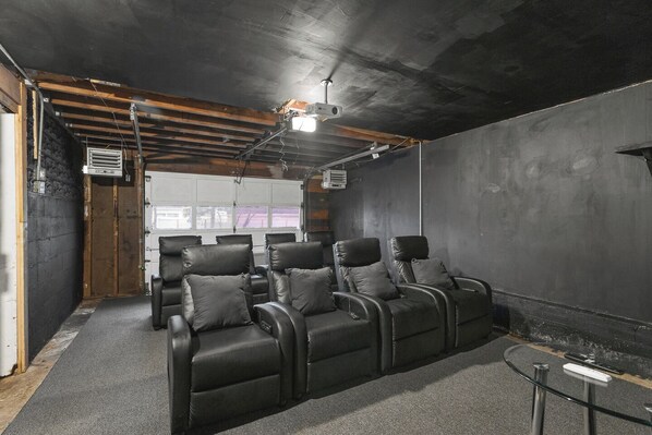 A room with a projector, a white door, and a seating area with black chairs.