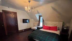 A bedroom with a bed, a nightstand, a chair, a television, and a chandelier. - Long Term- Monthly/Yearly (Bradford)