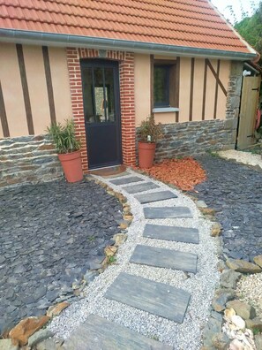 A building with a stone facade, a black door, and a gravel pathway leading to the entrance. - Haven of peace in the middle of nature, ecological house (Tirepied-sur-Sée)