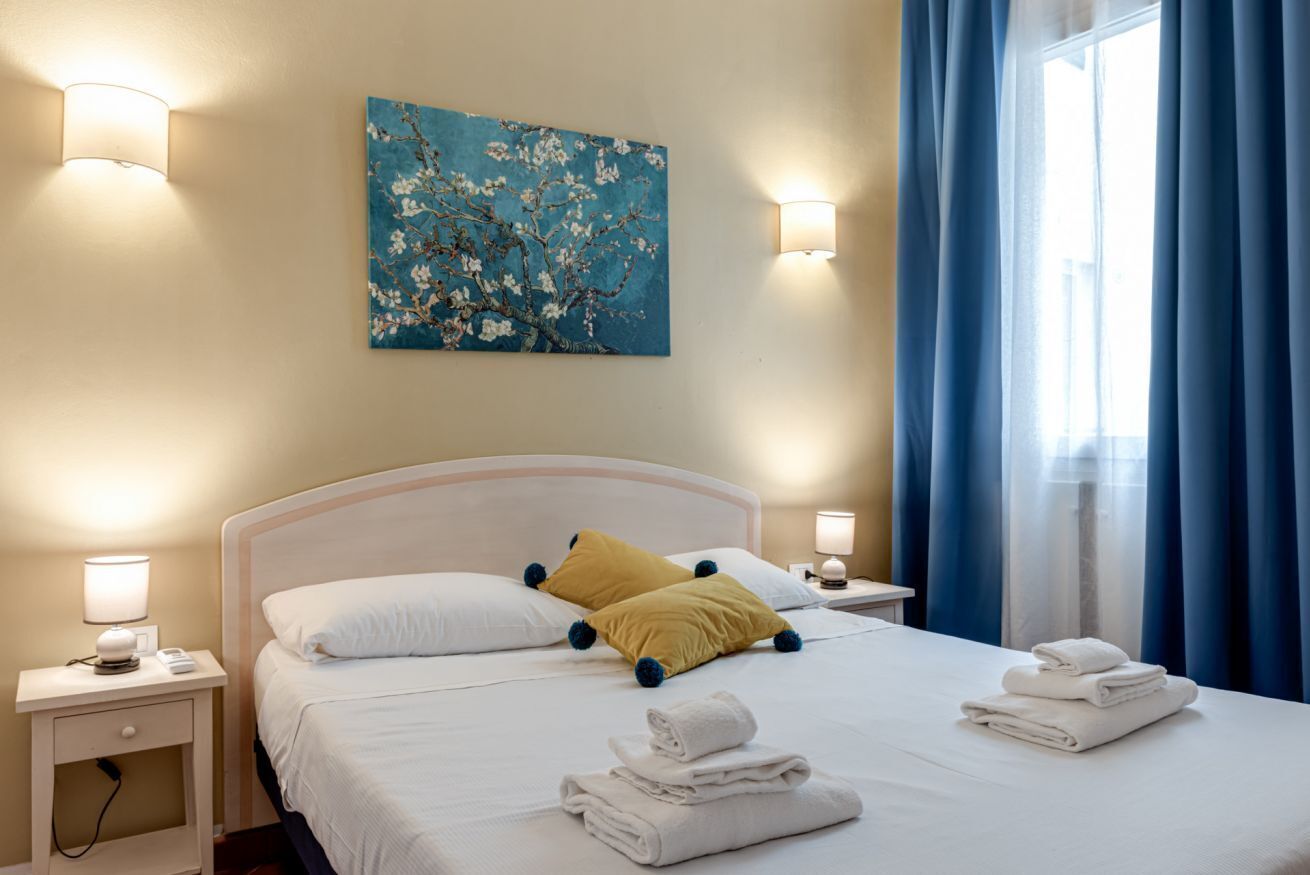 Une chambre d’hôtel avec un lit, un tableau et une fenêtre avec des rideaux.