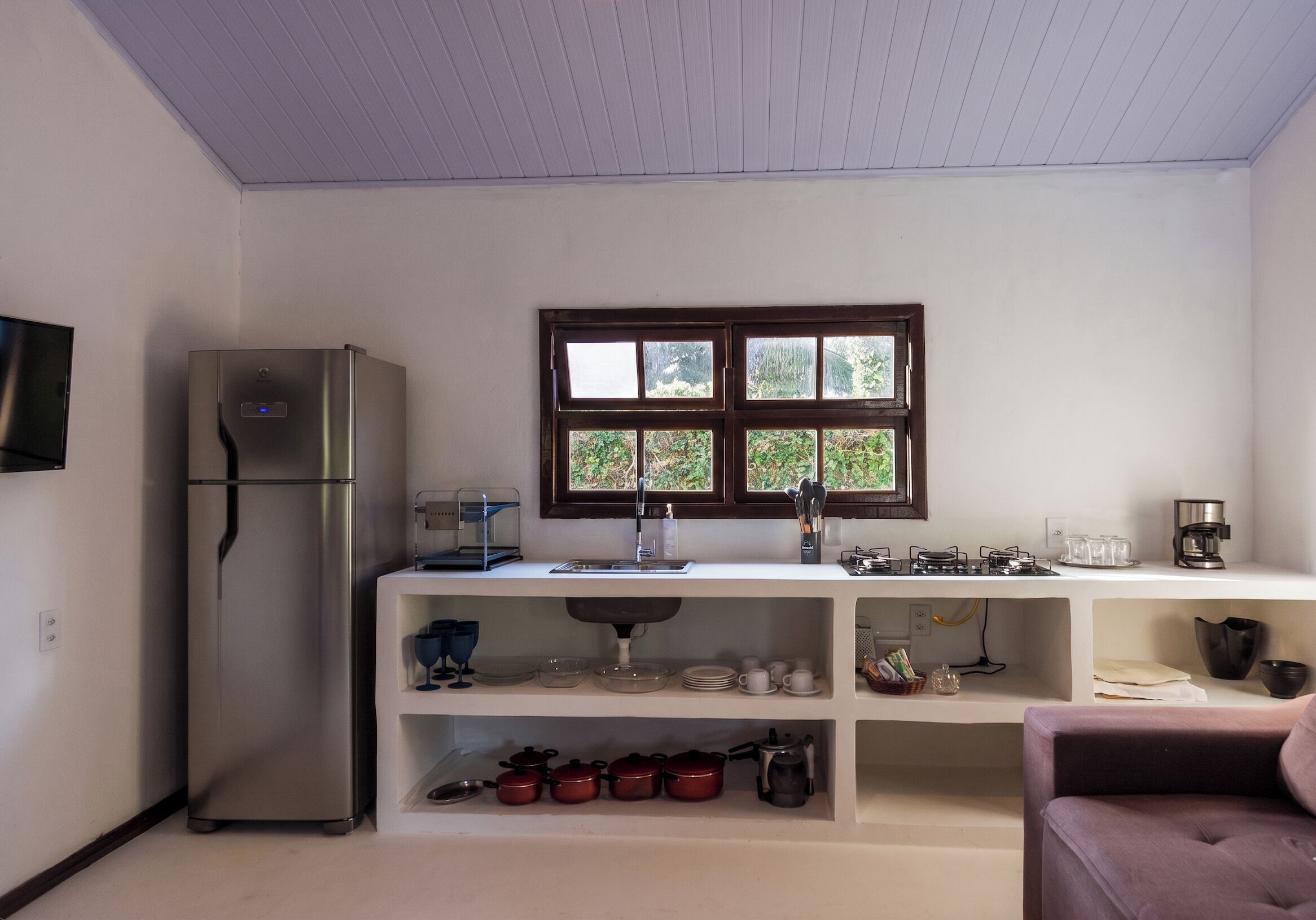 A compact kitchen with a refrigerator, a window with a view, a sink, and a coffee maker.
