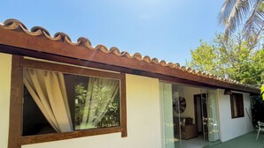 A single-story building with a tiled roof, large glass windows, and a green exterior wall. - Azorai Hotel Boutique (Santa Cruz Cabrália)