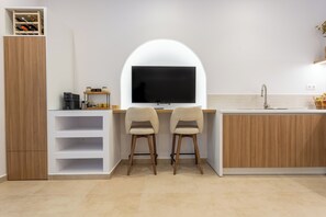 A modern kitchen with a built-in TV, two chairs, a coffee machine, and a wine rack. - Petite Nest - Mikrolimano (Pireas)