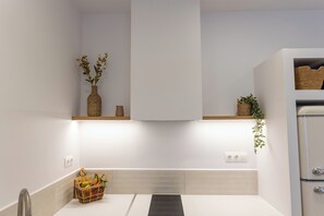 A modern bathroom with a white sink, a mirror, a towel rack, and a shower area. - Petite Nest - Mikrolimano (Pireas)