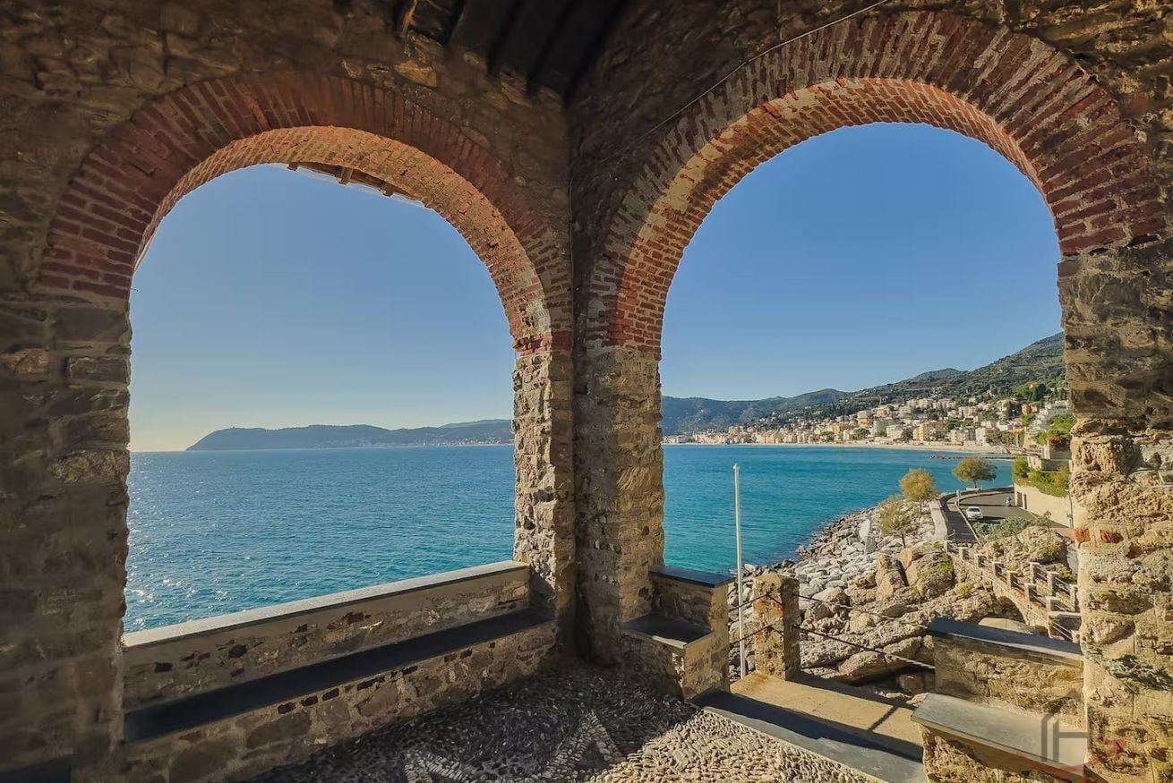 Eine gewölbte Steinstruktur mit Blick auf das Meer und eine Küstenstadt.