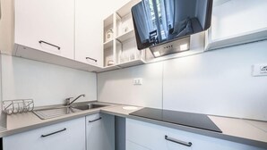 Une cuisine moderne avec des armoires blanches, un évier en acier inoxydable et un four encastré.
