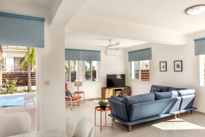Ein modernes Wohnzimmer mit einer Couch, einem Fernseher und einem kleinen Tisch mit einer Pflanze.