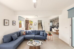 Ein modernes Wohnzimmer mit einem Ecksofa, einem runden Couchtisch und einer Treppe, die zur Küche führt.