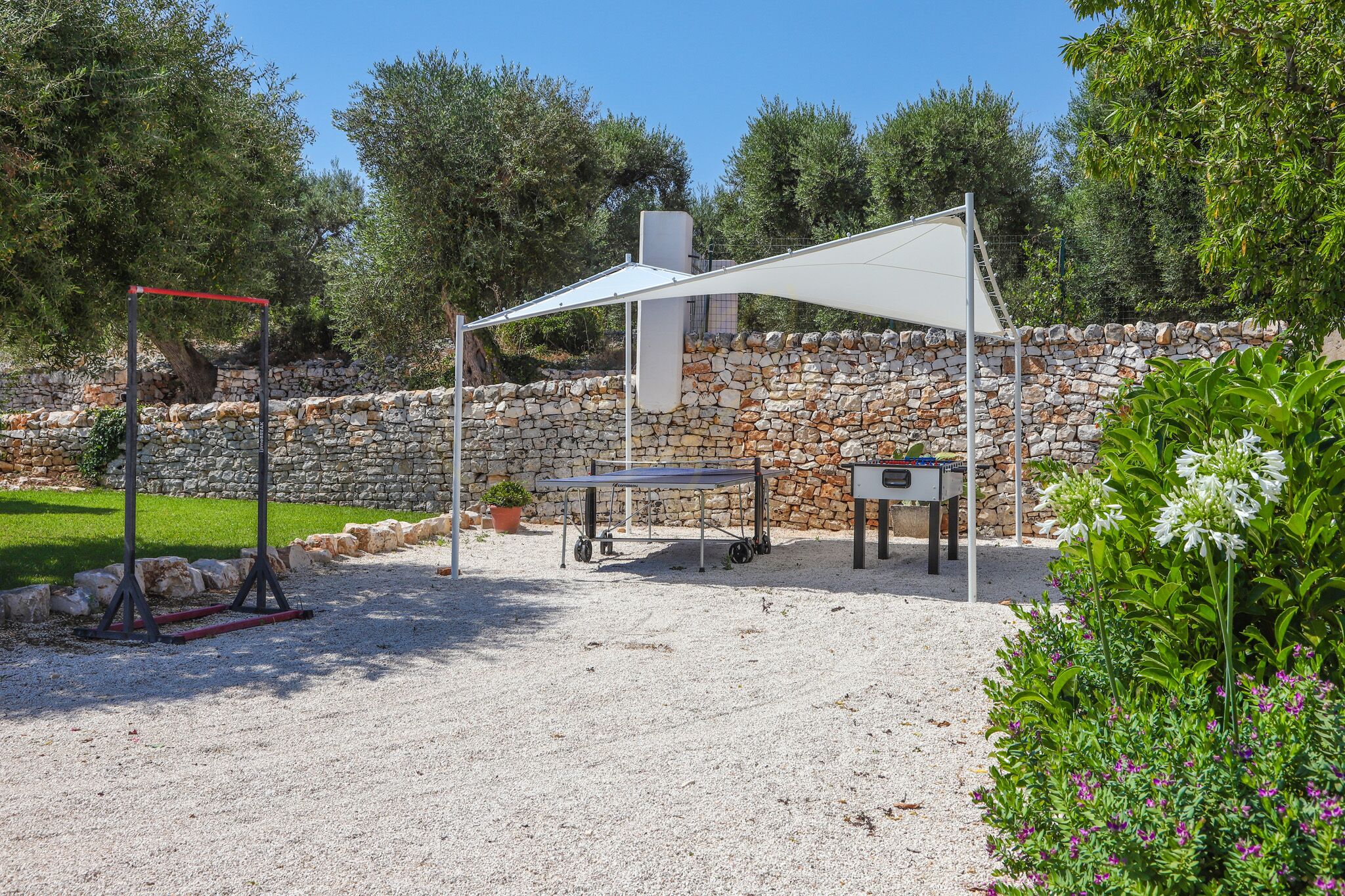 Un espace extérieur aménagé avec une table, des chaises, un barbecue et une pergola offrant de l’ombre.