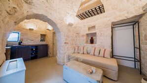 A stone-walled room with a sofa, a small table, and a window. - TD Trullo Lumina Boutique Luxury Trulli With Pool (Ostuni)
