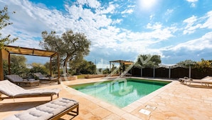 Ein Poolbereich mit Liegestühlen und einer Pergola.