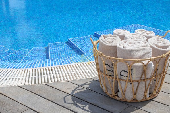 A poolside area with a wicker basket of towels and a wooden deck.
