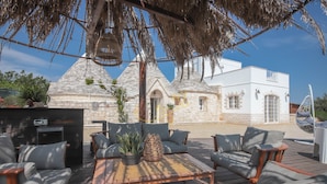 An outdoor seating area with a stone building in the background. - TD Trulli Bruco Large Pool for Family Fun (Monopoli)