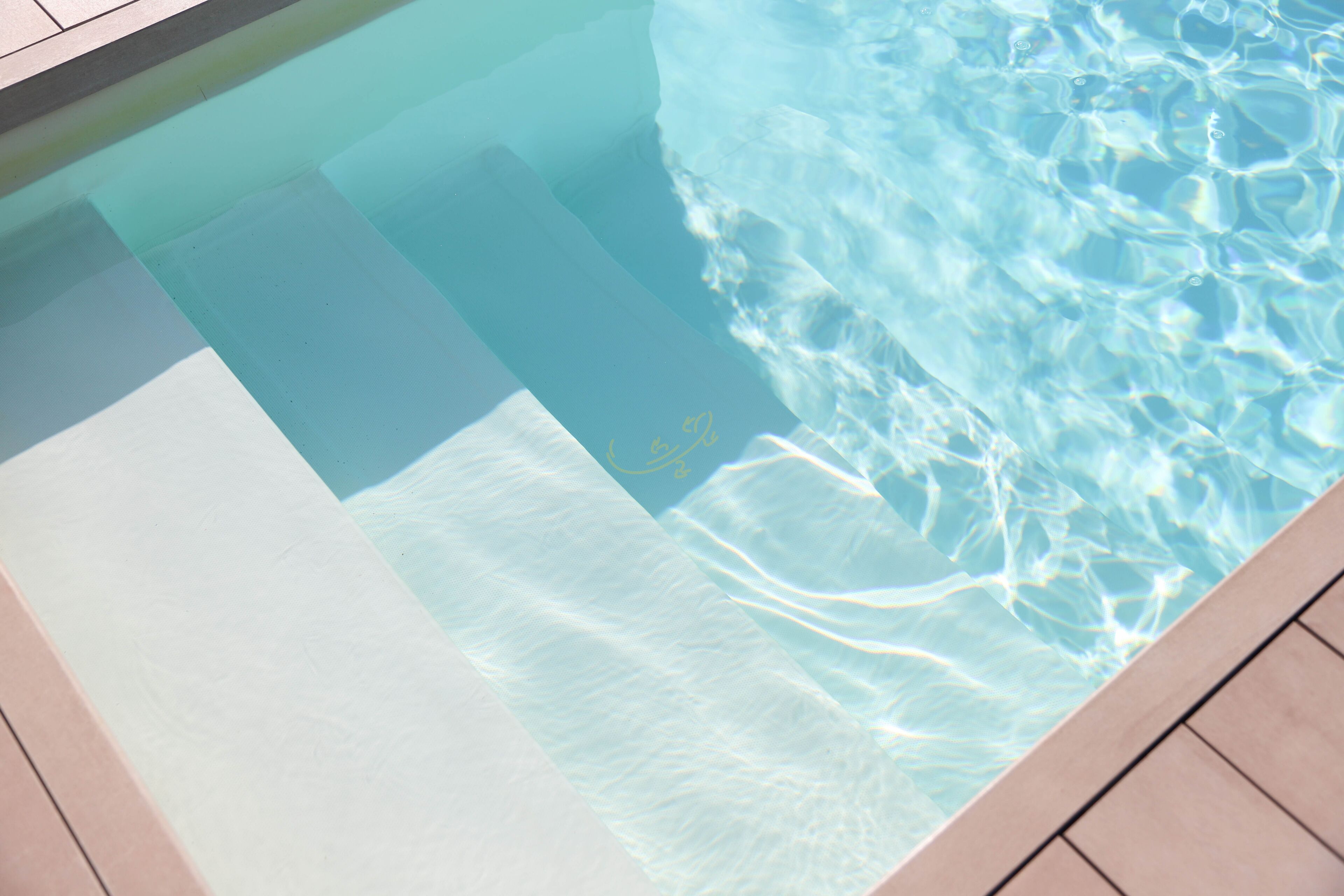 Una piscina con agua cristalina y suelo de baldosas.