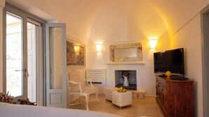 A cozy room with a fireplace, a television, and a seating area with a chair and ottoman. - TD Trullo Buenavista Stunning Valley Views W/pool (Ostuni)